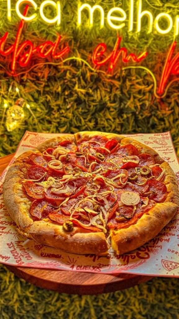 Pizza do Pier 307 com calabresa, cebola e azeitonas, frente ao muro verde